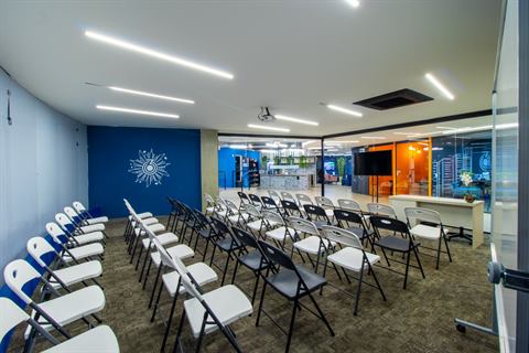 Auditório com cadeiras e o símbolo 360 na parede azul