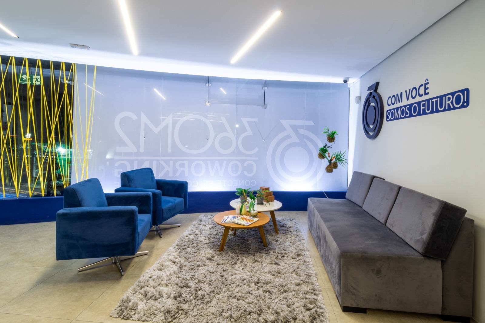 Recepção da sede, com poltronas azuis e o lema Com você somos o futuro
